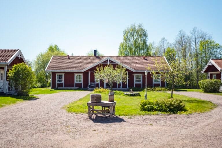 Boendets gårdsplan med grusväg, tre mysiga villor i ett plan samt gräsytor