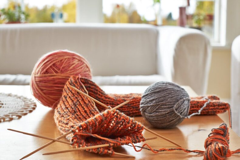 Detaljbild på garnnystan och stickor