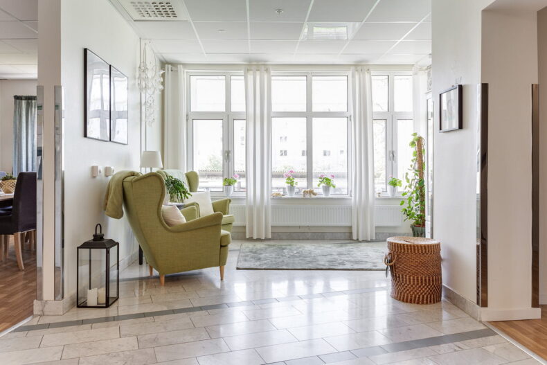 En gemensam yta med fåtöljer, fluffiga mattor och stora ljusa fönster