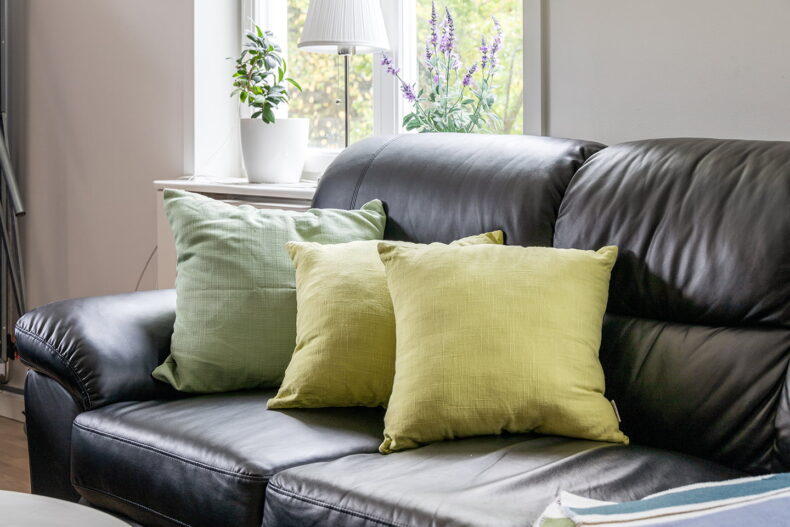 Närbild på en svart soffa med gröna kuddar