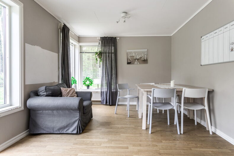 En gemensam matplats med liten soffa bredvid. På väggen hänger en whiteboard med ett veckoschema