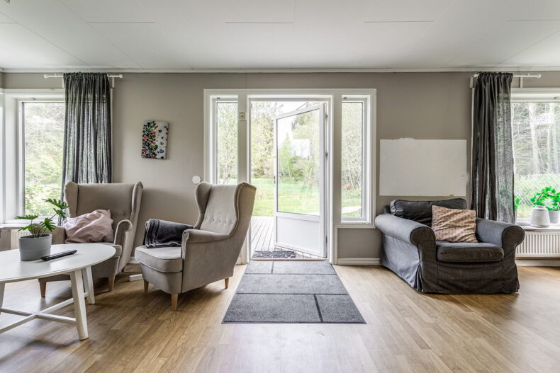 Gemensamt utrymme med fåtöljer, dekorativa textiler och utgång till altan