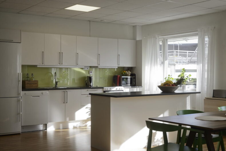 Ett gemensamt kök med matplats och ljusa fönster