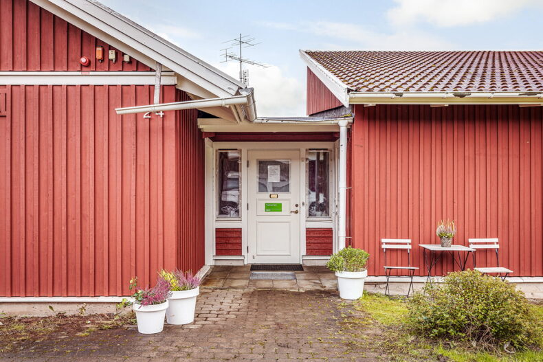 Boendets entré mellan röda utbyggnader