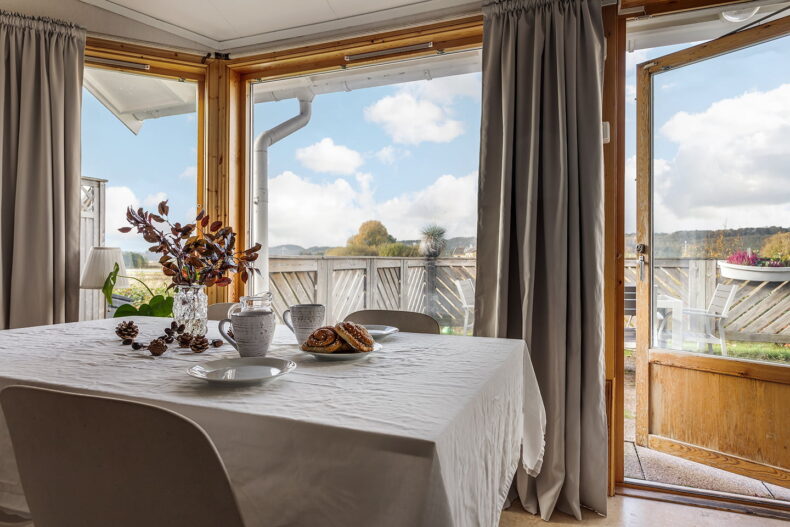 Uppdukad matplats med fika. Till höger öppen dörr till uteplats