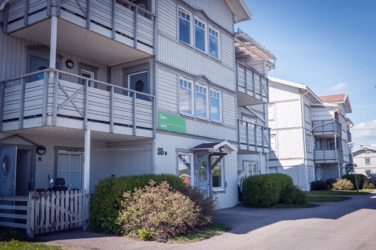 Öjebos grå fasad i tre våningar med balkonger.