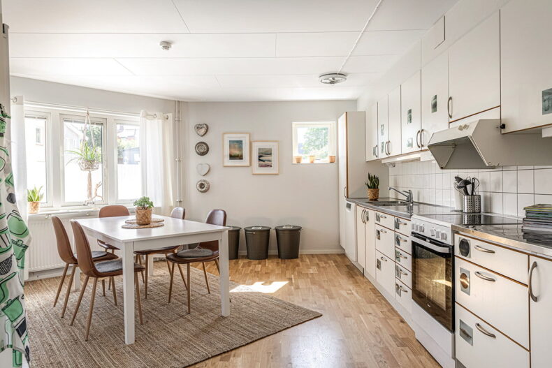 Stort kök med växter i fönstren och tavlor på väggen