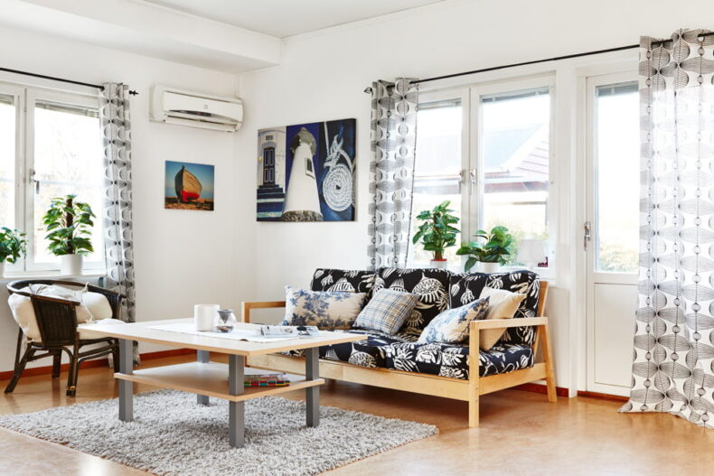 En gemensam yta med soffgrupp, bord, växter i fönstren och tavlor på väggarna
