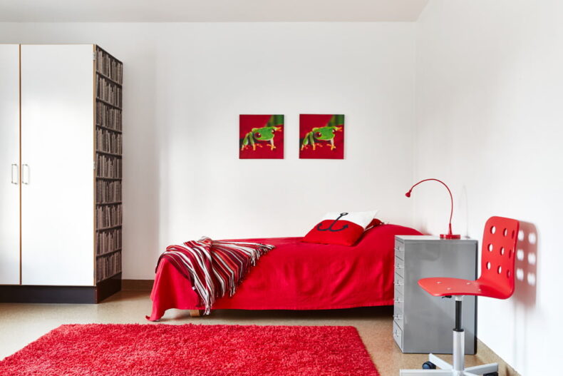 En av boendets lägenheter med säng, nattduksbord, garderob och en stol.