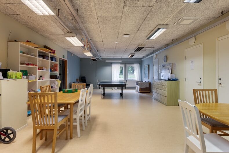Matplatser i verksamhetens kök i förgrunden samt ett pingisbord längre bort i det stora rummet