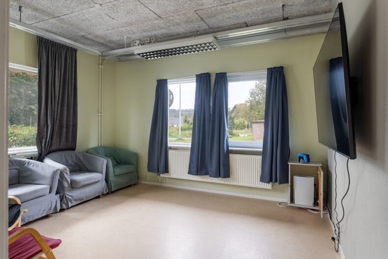 En TV-hörna med fåtöljer och mörkläggningsgardiner