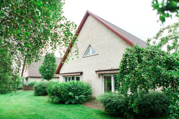 Gaveln på ett av boendehusen, med gul fasad och rödvita markiser. Framför finns buskar och gräsmatta