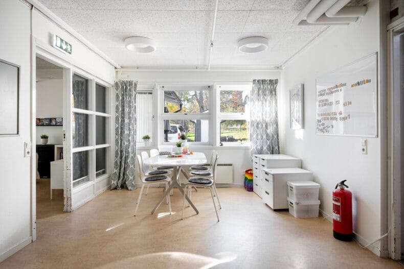 Ett genomgångsrum med ett bord för pyssel och flera byråar med material