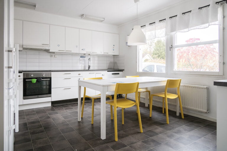 vitt kök, vitt bord och gula stolar