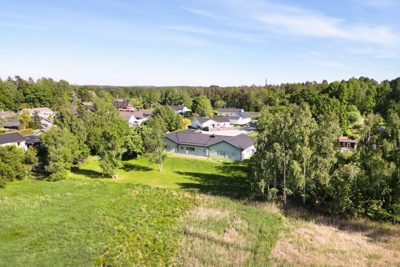 Ett flygfoto av boendet omgivet av träd och fält