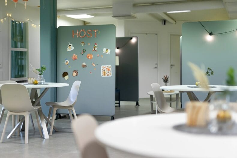 Verksamhetens matsal med runda bord och blå avdelnings-väggar med dekaler