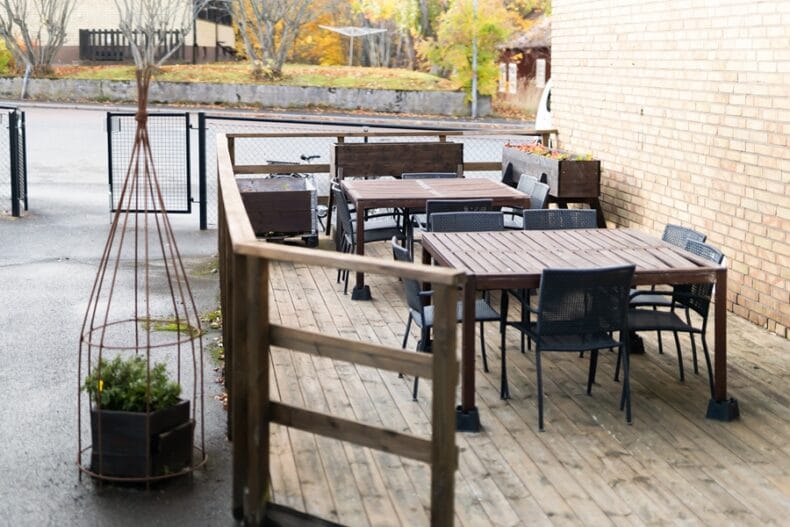 Verksamhetens uteplats, ett trädäck med rejäla bord och svarta stolar