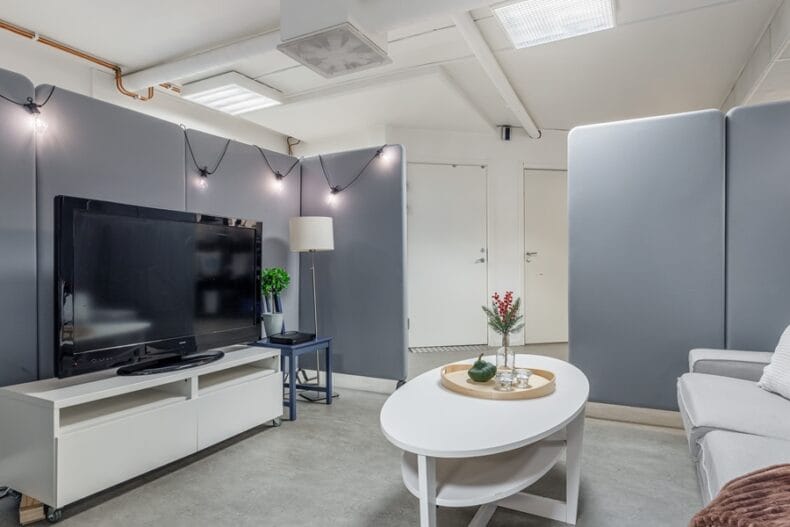 Ett TV-rum med soffa, soffbord och ljuddämpande skärmar runtom