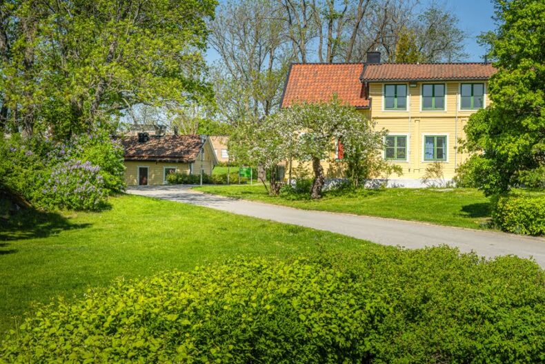 Boendet med gångväg, gräsmatta och fruktträd i förgrunden