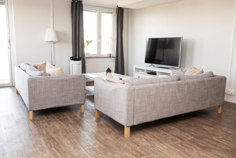 TV-hörna i ljust rum med två grå soffor och vitt soffbord