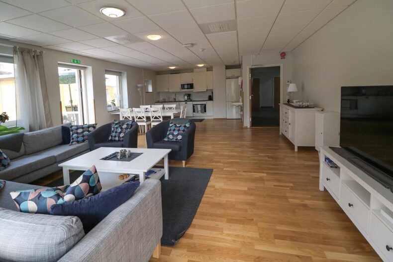 Boendets gemensamma ytor med en TV-hörna i förgrunden och kök med matplats i bakgrunden