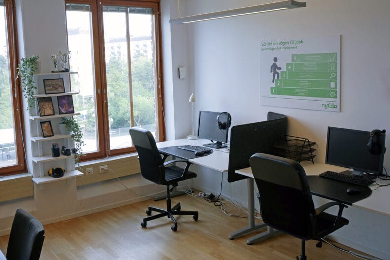 Studierummet med två skrivbord, datorskärmar och svarta kontorsstolar