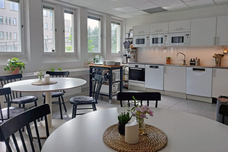 Köket med runda vita bord och svarta stolar