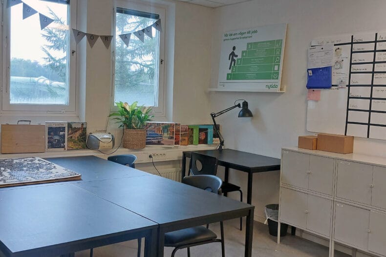 Rum men två svarta skrivbord, vit hutsch och flaggvimpel i fönstret