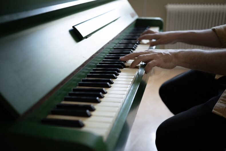 Närbild på en person som spelar på pianot i matsalen
