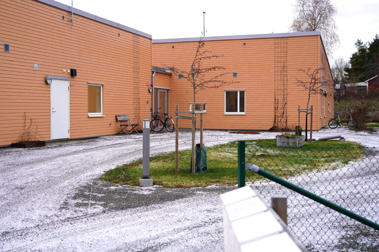 Boendets fasad, en tegelbyggnad med nyplanterade träd utanför