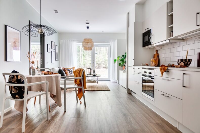 Kök med hemtrevlig möblering och öppen planlösning till vardagsrummet med dörr till uteplats.