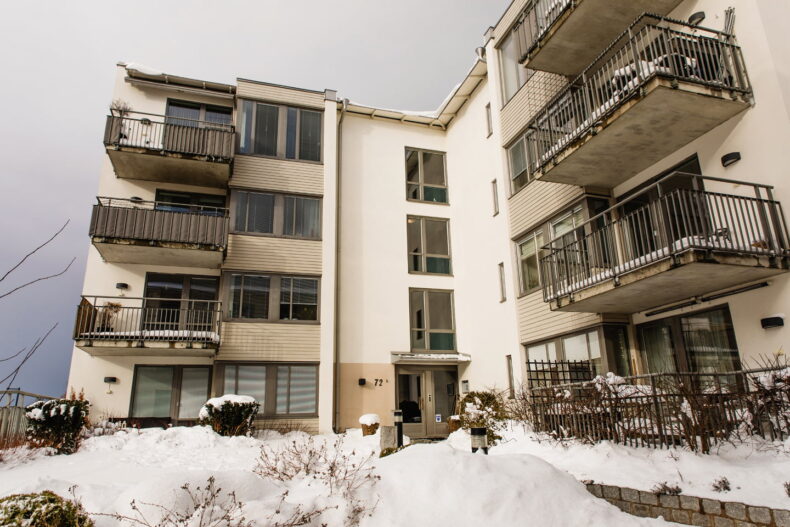 Boendet i vinterskrud. Lägenhetshus med fyra våningar och stora balkonger.