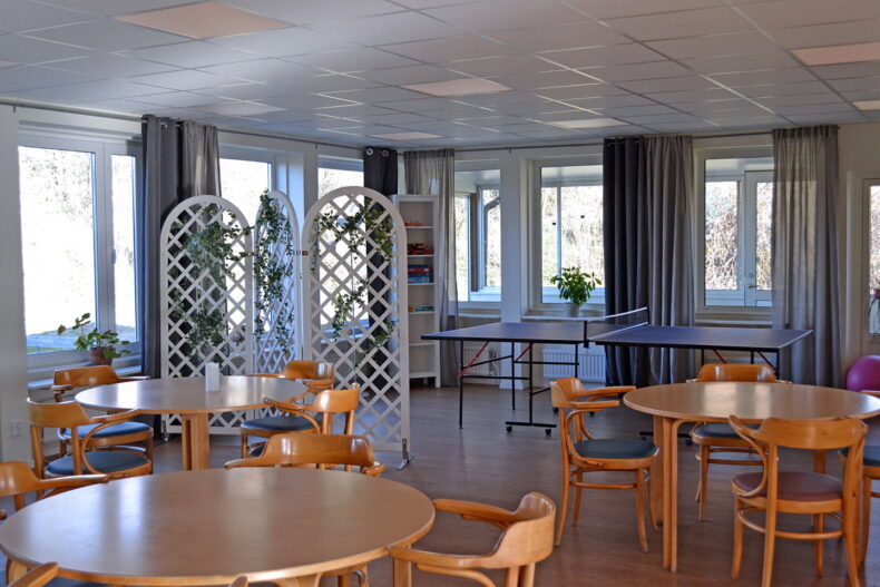 Boendets matsal med flera runda bord. I bakgrunden står ett pingisbord