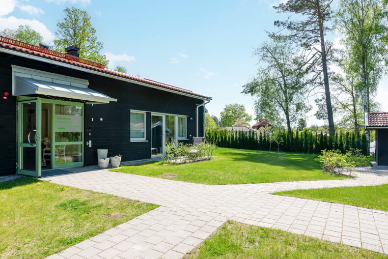 Boendets fasad med stenlagd gång utanför