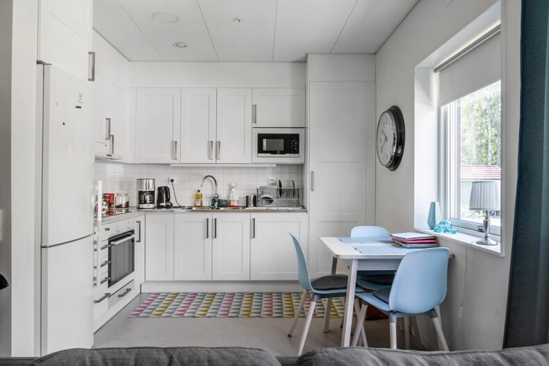 Köket i en av lägenheterna, med en matplats vid fönstret och en stor klocka på väggen