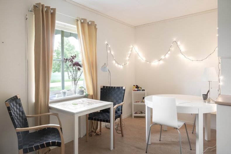 En av boendets lägenheter med två bord med stolar. På vägen hänger stämningsfull belysning