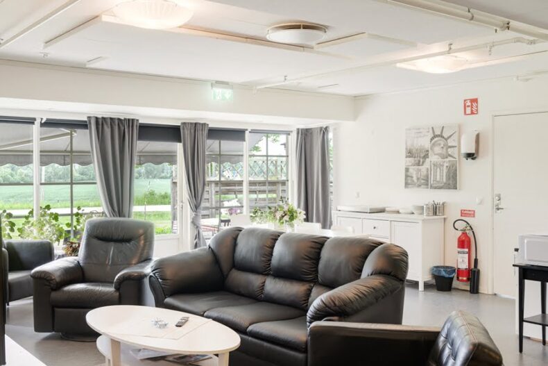 En gemensam yta med fåtöljer och soffa. I bakgrunden syns en uteplats