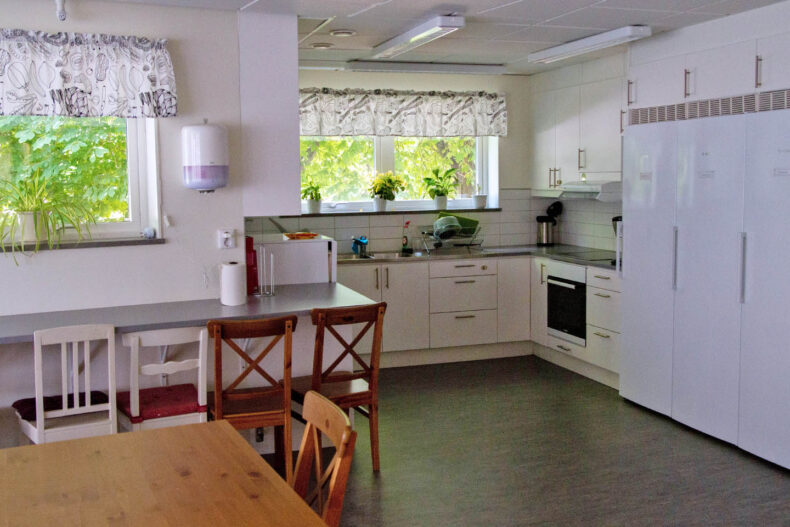 Baslägenhetens kök med bardisk vid väggen samt fristående matplats