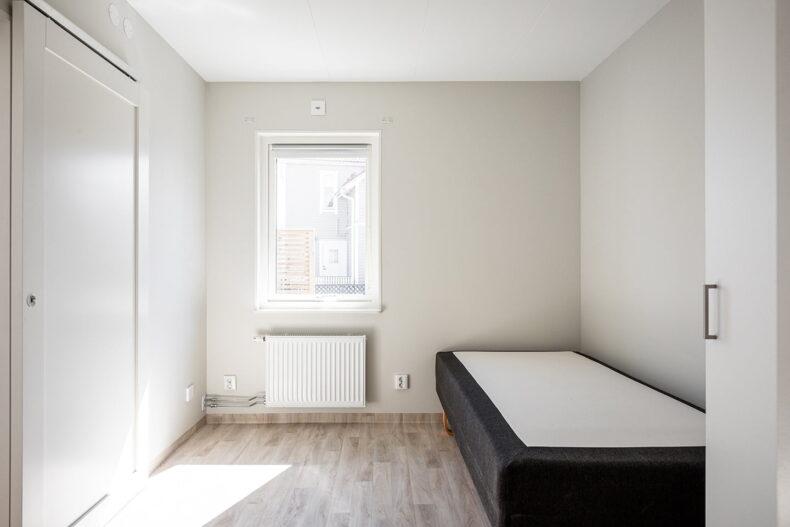 Sovrum med säng och garderob i en av boendets lägenheter.