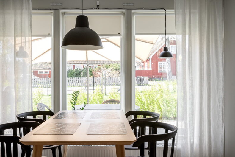 Matplatsen i boendets gemensamma kök framför stora ljusa fönster med uteplats, häck och gräsmatta utanför