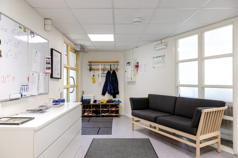 Ytan innanför entrén, med skohylla, soffa, byrå samt en whiteboard