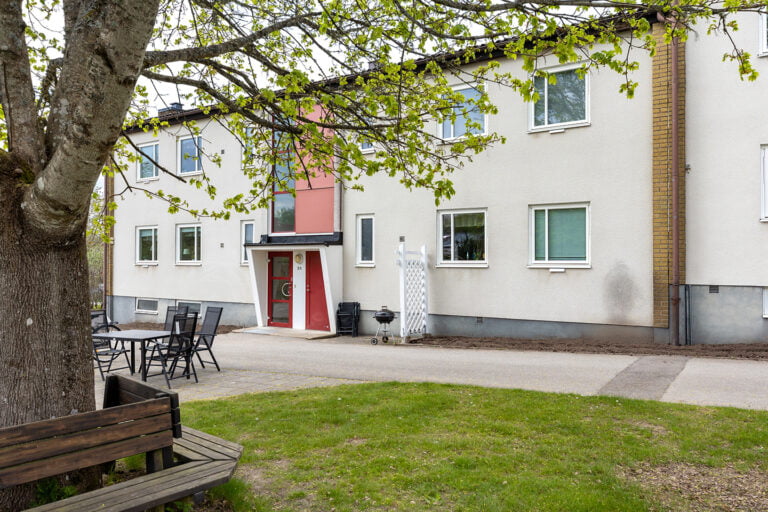 Boendets fasad, en lång ljus lägenhetsbyggnad i två våningar