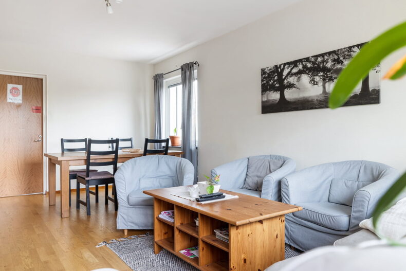 Fåtöljer och soffbord i förgrunden, med matplats bakom.