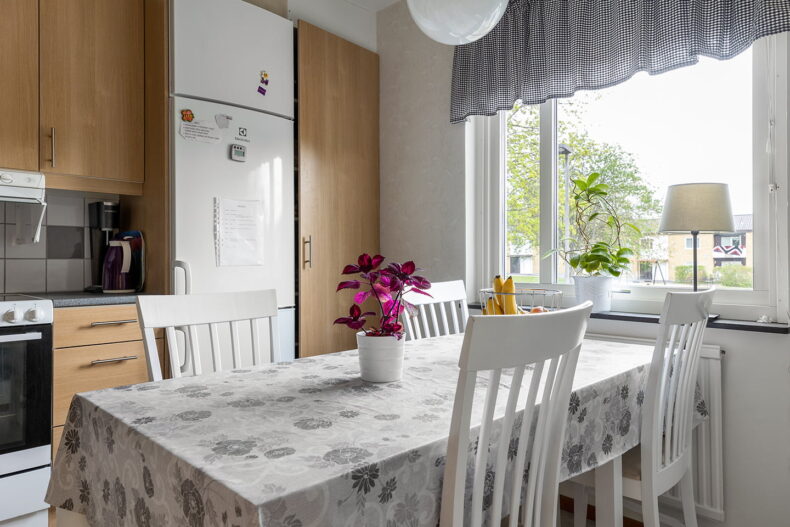 Matbord med blommig duk och fruktskål ovanpå