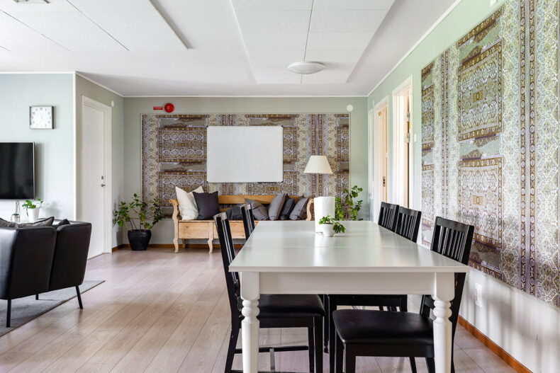 Matbord i förgrunden, soffa vid TV till vänster och äldre kökssoffa längst bort.