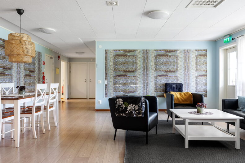 Gemensamt utrymme med vitt matbord till vänster och svart soffgrupp till höger