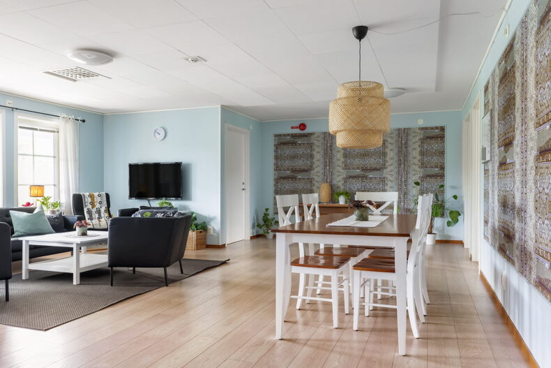 Gemensamt utrymme med blåa mönstrade väggar, matbord och TV-hörna.