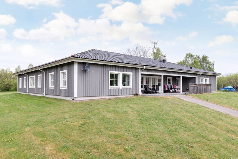 Boendets grå enplanshus med gräsytor runt omkring.