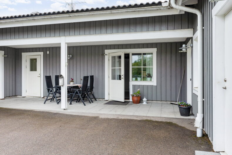 Stenlagd uteplats under tak mellan två ytterdörrar.