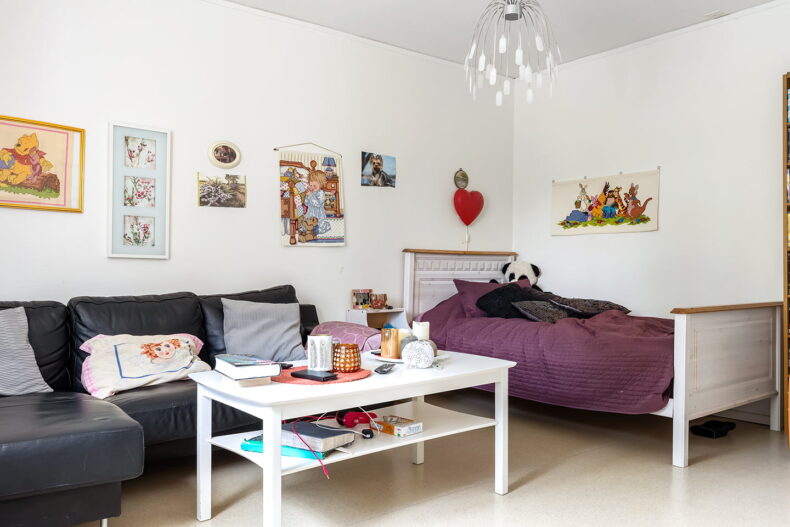 Lägenhet med soffa, soffbord, säng, samt många tavlor med Nalle Puh-motiv.